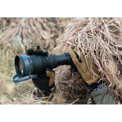 Osoba v maskovacom oblečení používa nočné videnie Armasight Sirius Gen 2+ SDi MG. Zariadenie je kompaktné a odolné, vhodné pre profesionálne použitie v teréne. Má čiernu farbu a je držané v rukaviciach, čo naznačuje jeho použitie v náročných podmienkach.