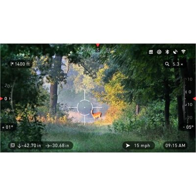 Pohľad cez smart spektív ATN X-SPOTTER HD 20-80x s nočným videním na lesnú scenériu so srncom. Displej zobrazuje rôzne údaje ako zväčšenie, smer, rýchlosť vetra a čas.