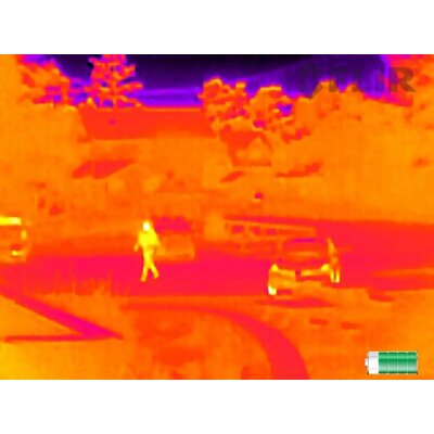 Termovízny pohľad z kamery FLIR Scout TK, zobrazený obraz s farebnou paletou InstAlert, na ktorom sú vidieť osoby a vozidlá v teréne.