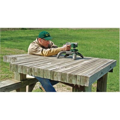 Muž nastavuje pištoľ na nastreľovacom stojane Handy Rest NXT na drevenom stole vonku na lúke.