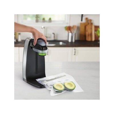Vákuová balička potravín FoodSaver FFS010X-01 s rukou používateľa počas vákuovania avokáda v kuchyni.