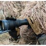 Osoba v maskovacom oblečení používa nočné videnie Armasight Sirius Gen 2+ SDi MG. Zariadenie je kompaktné a odolné, vhodné pre profesionálne použitie v teréne. Má čiernu farbu a je držané v rukaviciach, čo naznačuje jeho použitie v náročných podmienkach.